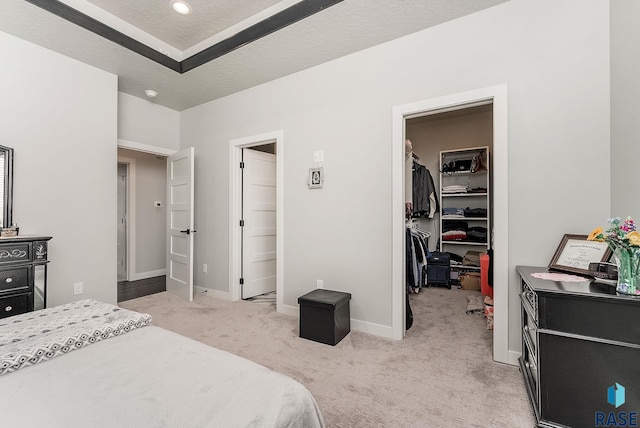 bedroom featuring a textured ceiling, light colored carpet, baseboards, a spacious closet, and a closet