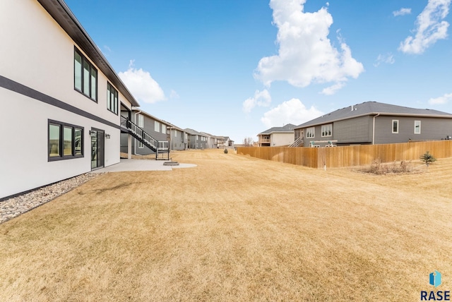 view of yard featuring a patio area, fence, and a residential view