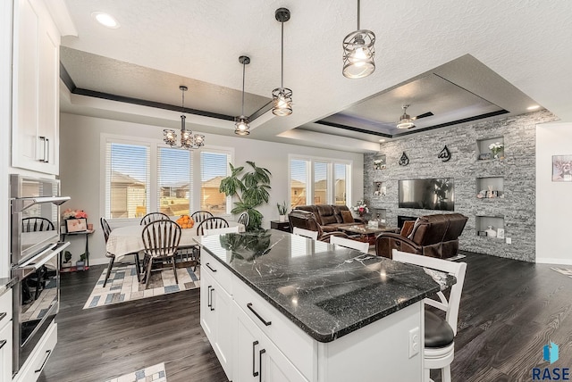 kitchen featuring a fireplace, a tray ceiling, dark wood-type flooring, and a textured ceiling