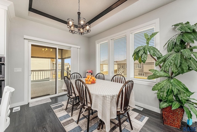 dining area featuring baseboards, a tray ceiling, dark wood finished floors, and a chandelier