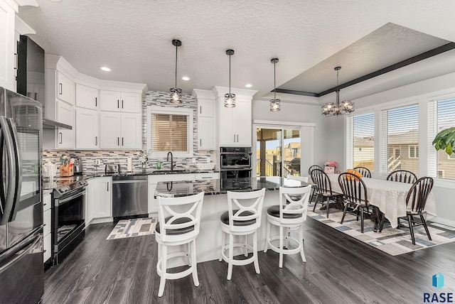 kitchen with decorative backsplash, dark wood-style floors, a kitchen island, appliances with stainless steel finishes, and a sink