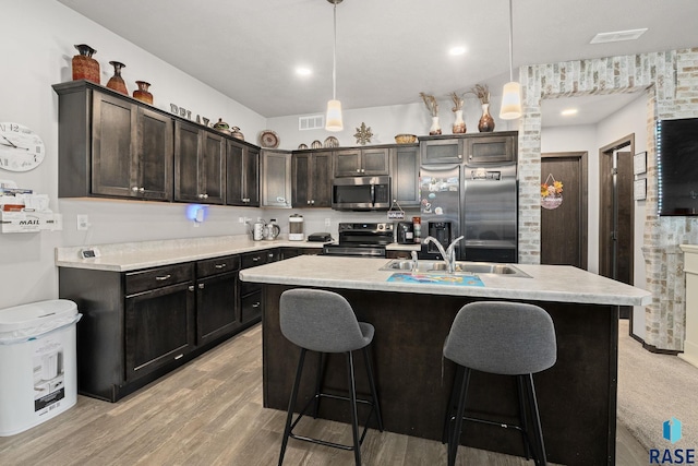 kitchen featuring stainless steel appliances, a sink, light countertops, and a kitchen breakfast bar