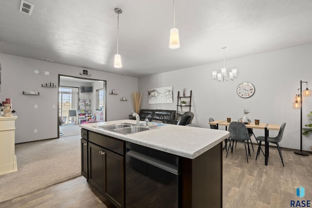 kitchen with light wood finished floors, visible vents, dishwashing machine, light countertops, and a sink