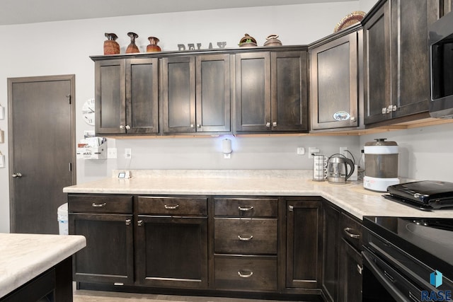 kitchen featuring dark brown cabinets, stainless steel microwave, and light countertops