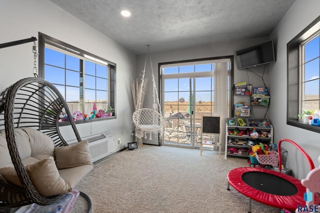 game room with a textured ceiling, carpet floors, and a wall mounted AC