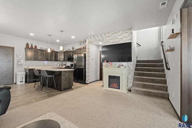 kitchen featuring a breakfast bar, visible vents, open floor plan, light countertops, and black fridge