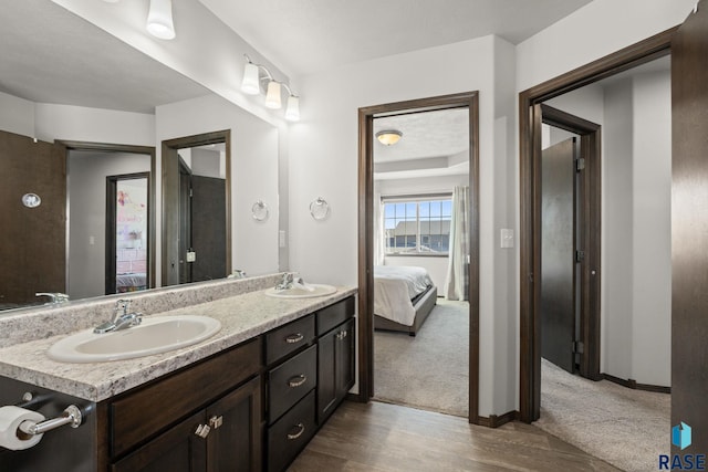 ensuite bathroom with wood finished floors, double vanity, a sink, and ensuite bathroom