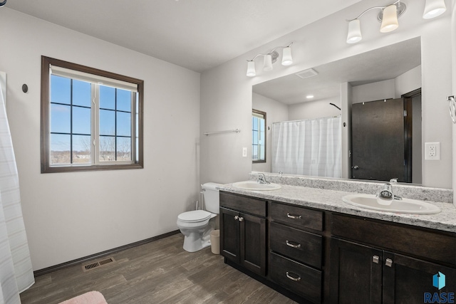 bathroom with toilet, visible vents, a sink, and wood finished floors