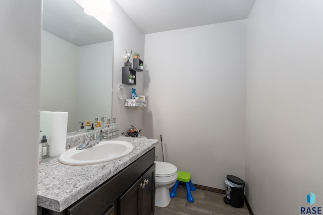 bathroom with baseboards, vanity, toilet, and wood finished floors