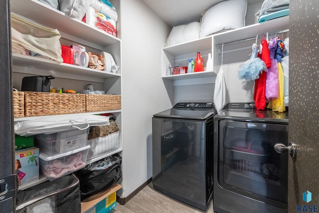 laundry area with laundry area, baseboards, washer and clothes dryer, and wood finished floors