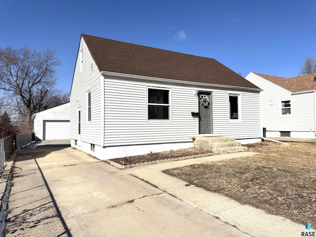 view of front facade featuring a garage, roof with shingles, fence, and an outbuilding