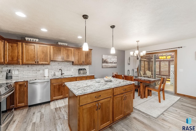 kitchen with light wood-style flooring, appliances with stainless steel finishes, brown cabinetry, and backsplash