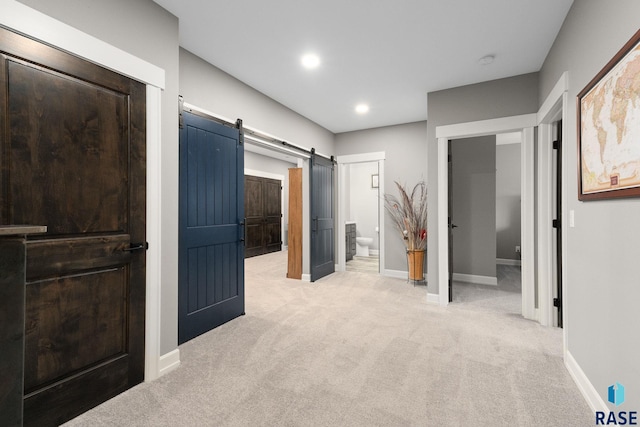 bedroom featuring a barn door, connected bathroom, recessed lighting, light colored carpet, and baseboards