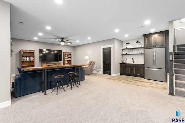 interior space with light colored carpet, freestanding refrigerator, stairs, indoor wet bar, and recessed lighting