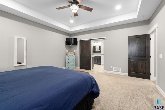 bedroom featuring visible vents, a barn door, light carpet, ensuite bath, and baseboards