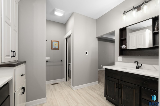 bathroom with wood finished floors, vanity, and baseboards