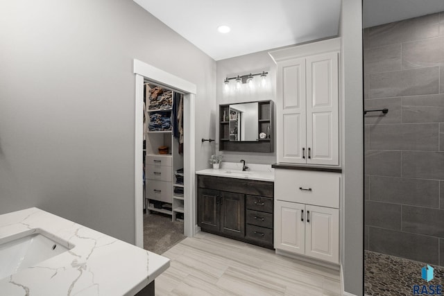 full bathroom featuring tiled shower, vanity, and a spacious closet