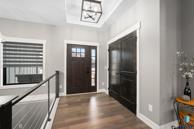 entrance foyer featuring a tray ceiling, hardwood / wood-style flooring, and baseboards