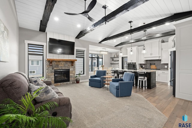 living room with a stone fireplace, light wood-type flooring, a ceiling fan, and recessed lighting