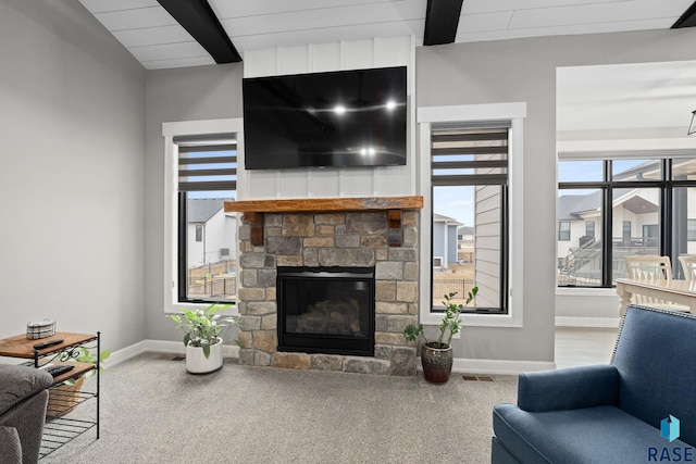 living area featuring a stone fireplace, beam ceiling, and baseboards