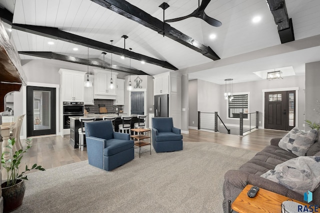 living area featuring light wood finished floors, high vaulted ceiling, and beamed ceiling