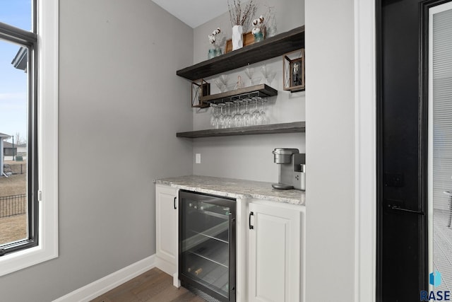 bar with dark wood-type flooring, wine cooler, baseboards, and a dry bar