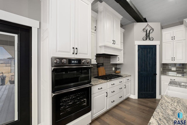 kitchen featuring white cabinetry, multiple ovens, and beam ceiling