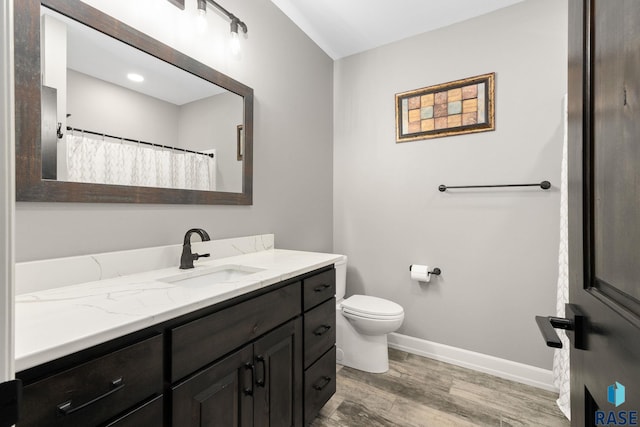 full bathroom with toilet, wood finished floors, vanity, and baseboards