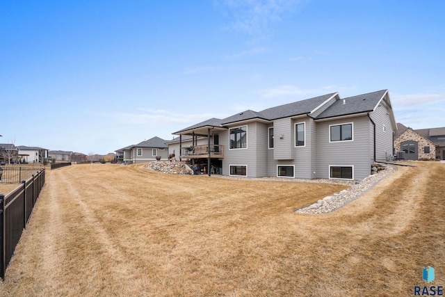 rear view of property featuring fence and a yard