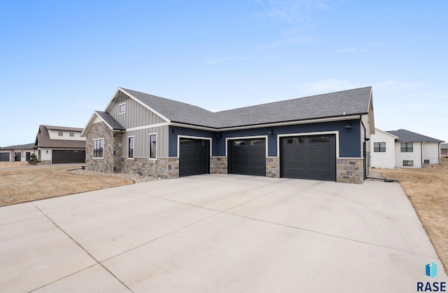 view of front of house with a shingled roof, board and batten siding, a garage, stone siding, and driveway