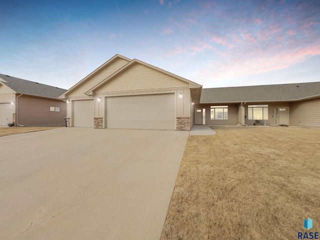 view of front of property featuring a garage, driveway, board and batten siding, and stone siding