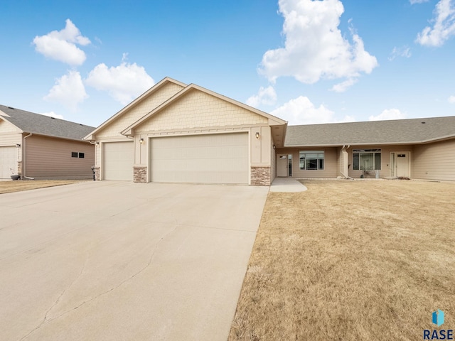 view of front of house with an attached garage, stone siding, concrete driveway, and a front yard