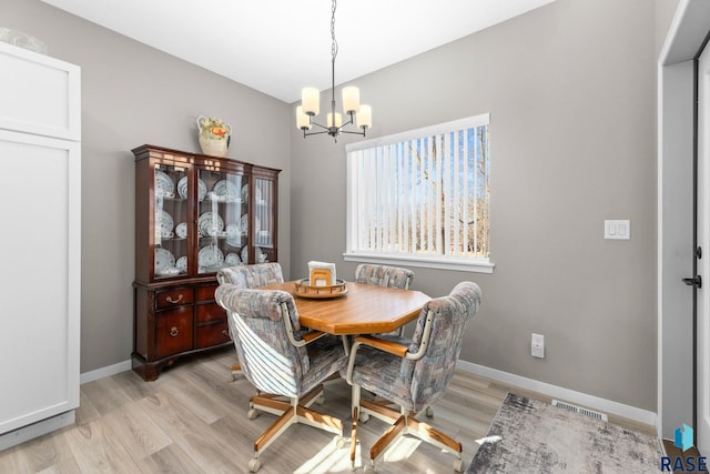 dining space with an inviting chandelier, light wood-style flooring, and baseboards