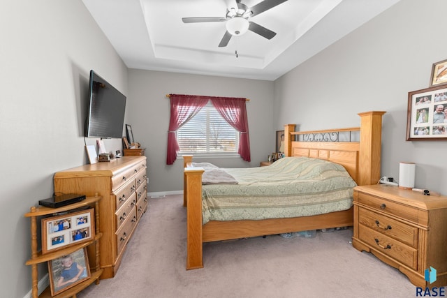 bedroom with light carpet, ceiling fan, baseboards, and a raised ceiling