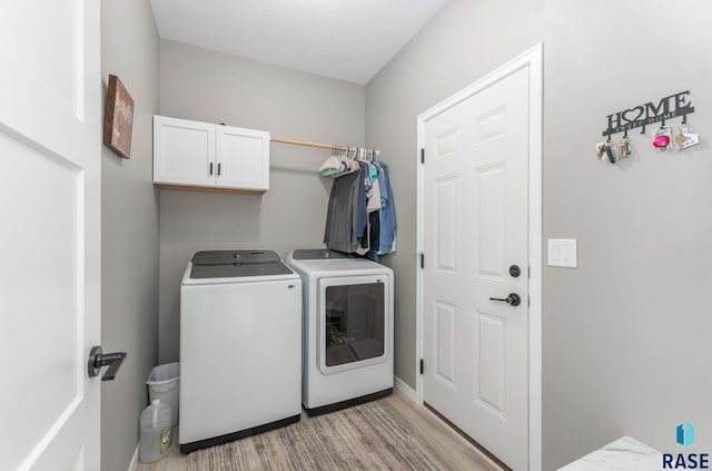 laundry room with light wood-type flooring, cabinet space, and washing machine and dryer