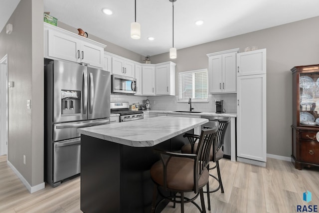 kitchen featuring white cabinets, appliances with stainless steel finishes, a center island, a sink, and backsplash