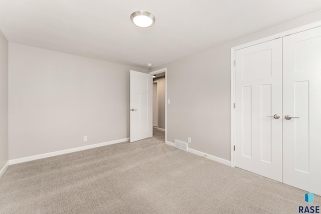 unfurnished bedroom with baseboards, visible vents, a closet, and light colored carpet