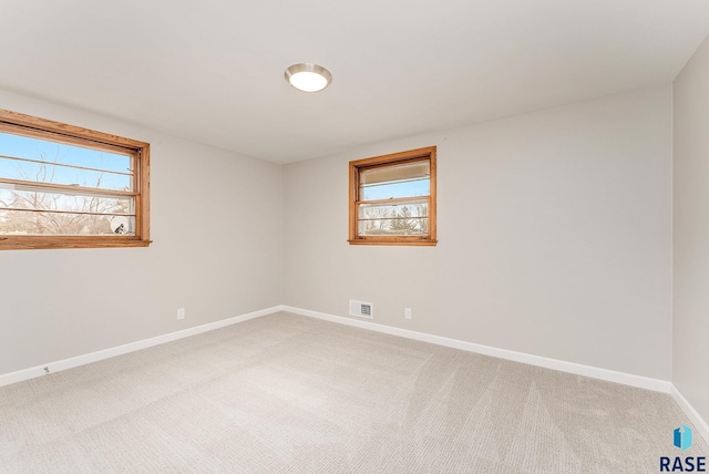 unfurnished room featuring baseboards, visible vents, and light colored carpet