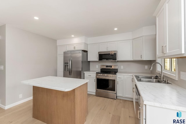 kitchen with white cabinets, appliances with stainless steel finishes, light countertops, light wood-style floors, and a sink