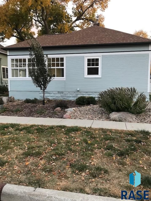 view of side of home with roof with shingles