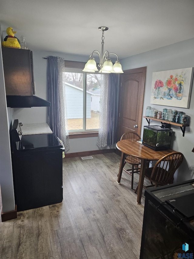 dining space with baseboards, visible vents, a chandelier, and wood finished floors