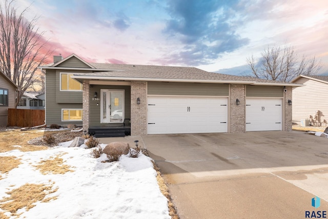 view of front facade featuring an attached garage, a shingled roof, concrete driveway, and brick siding