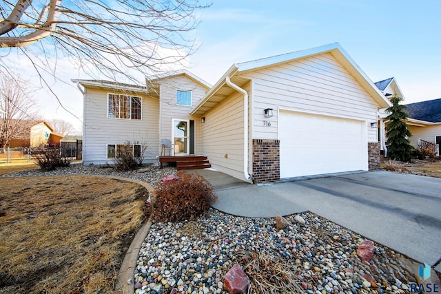 tri-level home with driveway, brick siding, and an attached garage