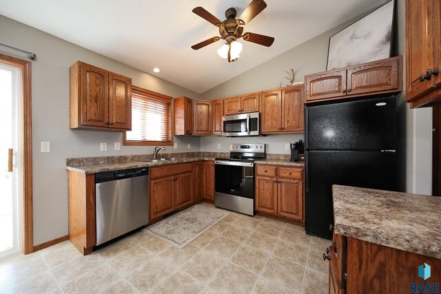 kitchen featuring a ceiling fan, lofted ceiling, appliances with stainless steel finishes, brown cabinets, and a sink