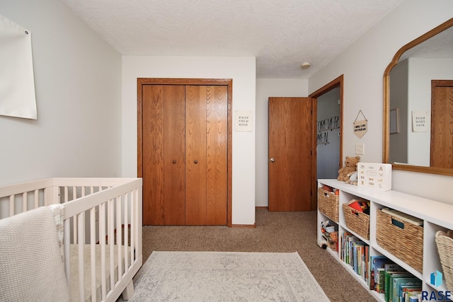 carpeted bedroom with a crib, a textured ceiling, and a closet