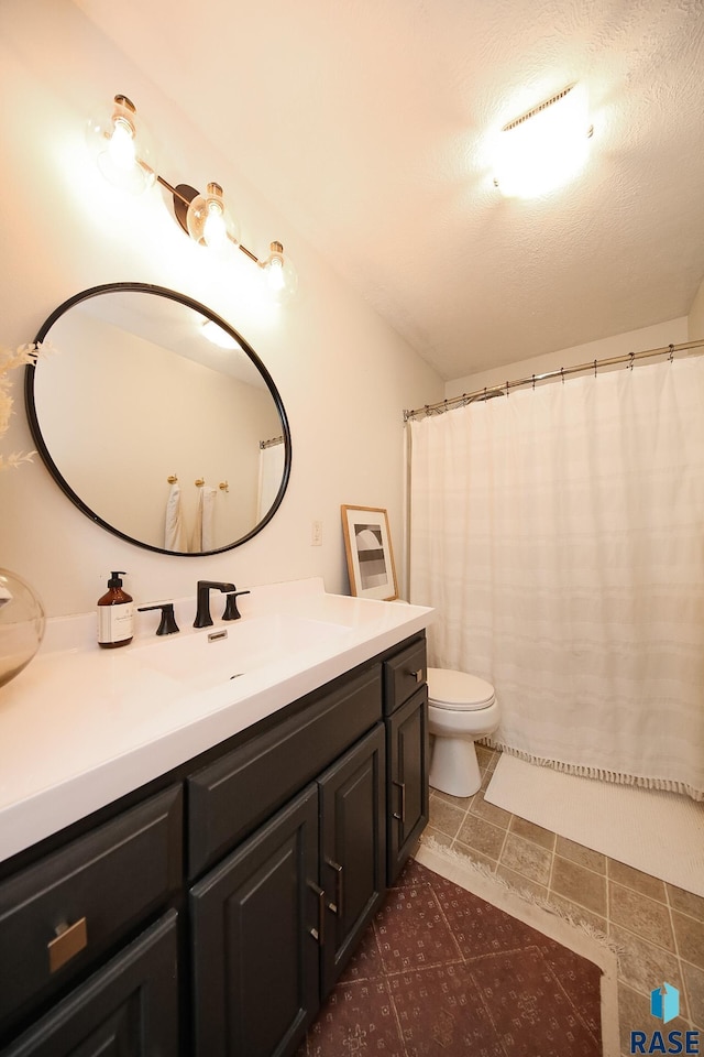 full bathroom featuring curtained shower, vanity, toilet, and a textured ceiling