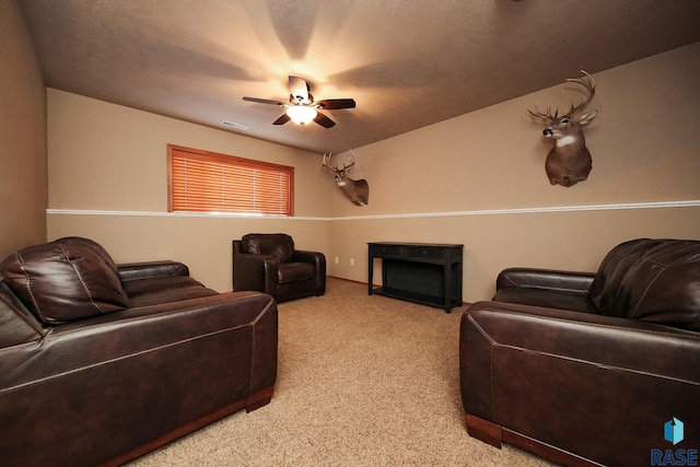 carpeted living room with a fireplace, visible vents, and a ceiling fan