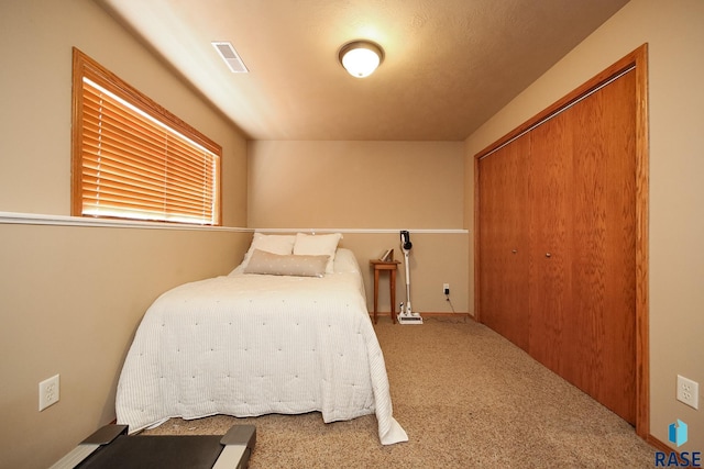 carpeted bedroom featuring a closet and visible vents