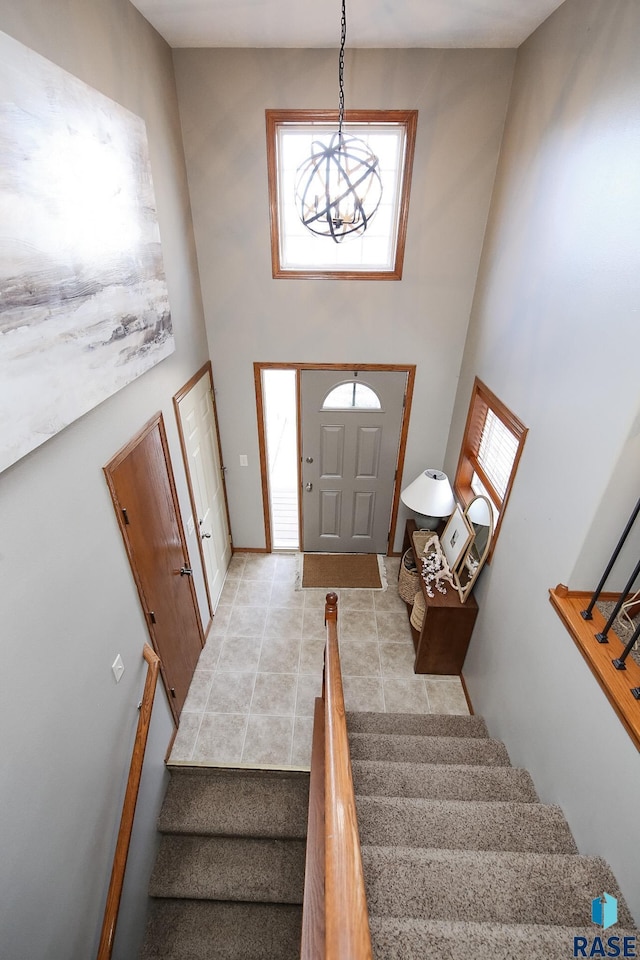 entrance foyer with light tile patterned flooring, stairway, and a towering ceiling