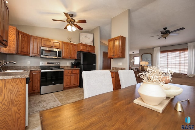 kitchen with stainless steel appliances, a ceiling fan, open floor plan, a sink, and vaulted ceiling